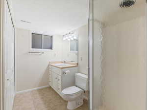 Bathroom with tile patterned floors, vanity, a textured ceiling, and toilet