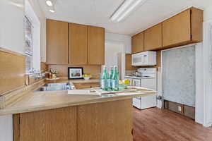 Kitchen featuring kitchen peninsula, white appliances, sink, and light hardwood / wood-style flooring