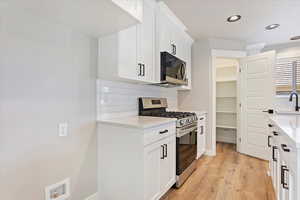 Kitchen featuring white cabinets, stainless steel appliances, light hardwood / wood-style flooring, and sink