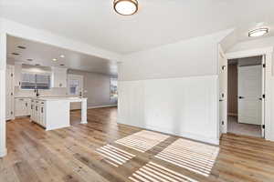 Kitchen featuring a center island, a kitchen breakfast bar, light wood-type flooring, tasteful backsplash, and white cabinetry