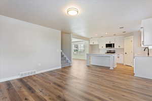 Kitchen with white cabinetry, sink, light hardwood / wood-style floors, a breakfast bar area, and appliances with stainless steel finishes