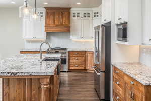 Kitchen with white cabinetry, a center island with sink, and high end appliances