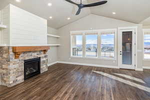 Unfurnished living room featuring a fireplace, ceiling fan, dark hardwood / wood-style flooring, and lofted ceiling