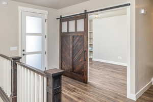 Interior space with a barn door and dark wood-type flooring