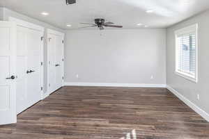 Unfurnished bedroom with ceiling fan, dark hardwood / wood-style flooring, a textured ceiling, and two closets