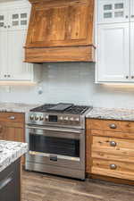 Kitchen featuring white cabinets, premium range hood, high end stainless steel range oven, and dark wood-type flooring