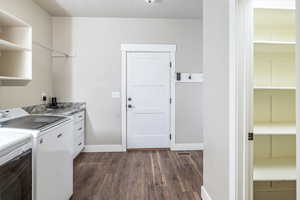 Washroom with dark hardwood / wood-style flooring, cabinets, and independent washer and dryer