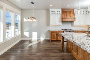 Kitchen with premium range hood, white cabinetry, high end stainless steel range, and plenty of natural light