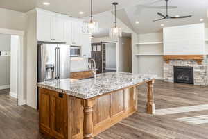 Kitchen featuring a large island with sink, sink, a barn door, white cabinetry, and stainless steel appliances