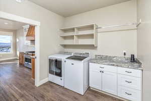 Washroom featuring washer and dryer, cabinets, and dark wood-type flooring