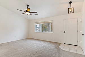 Foyer featuring ceiling fan, light colored carpet, and lofted ceiling