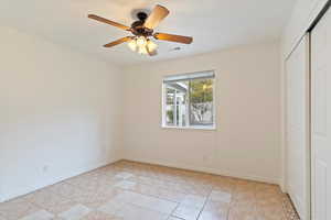 Unfurnished bedroom featuring ceiling fan, a closet, and light tile patterned floors