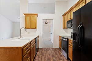 Kitchen featuring kitchen peninsula, dark hardwood / wood-style flooring, black appliances, and sink