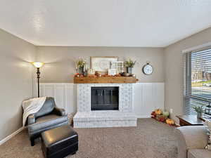 Living room with carpet, a textured ceiling, and a brick fireplace