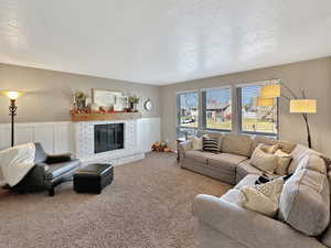 Carpeted living room featuring a textured ceiling and a brick fireplace