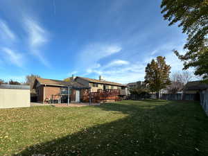 Back of property with a pergola, a yard, a storage shed, and a deck