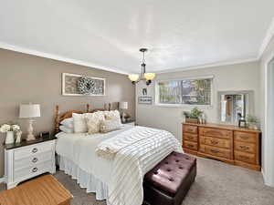 Bedroom featuring crown molding, carpet floors, a textured ceiling, and a notable chandelier