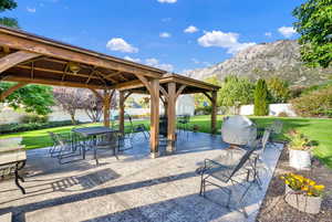 Surrounding community with a mountain view, a gazebo, a patio area, and a lawn