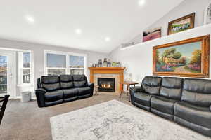 Carpeted living room featuring a wealth of natural light, lofted ceiling, and a tiled fireplace