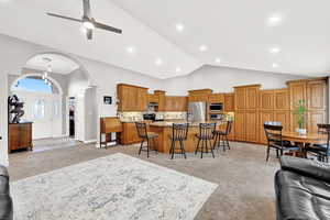 Living room featuring ceiling fan, high vaulted ceiling, and light colored carpet