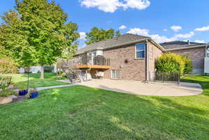 Rear view of property featuring a yard, a patio, and a deck