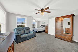 Bedroom with carpet, ceiling fan, a textured ceiling, and vaulted ceiling