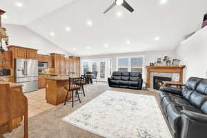 Carpeted living room with ceiling fan, sink, a tile fireplace, and vaulted ceiling