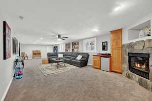 Living room with a textured ceiling, ceiling fan, light carpet, and bar area