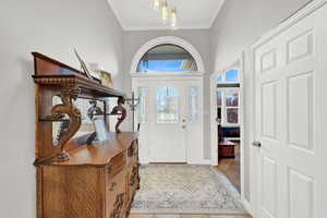 Entrance foyer featuring crown molding and light tile patterned flooring