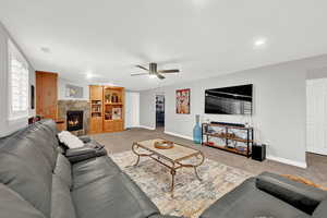 Carpeted living room featuring ceiling fan and a fireplace