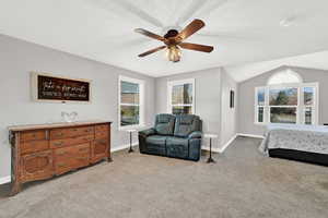 Carpeted bedroom featuring ceiling fan, a textured ceiling, and vaulted ceiling