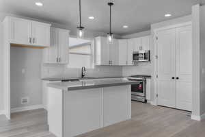 Kitchen with white cabinetry, a center island, pendant lighting, and appliances with stainless steel finishes