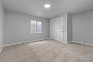 Unfurnished bedroom with light carpet and a closet