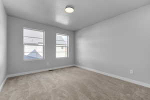 Carpeted spare room featuring a textured ceiling