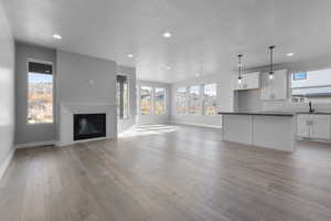 Unfurnished living room with a textured ceiling, light hardwood / wood-style floors, and sink