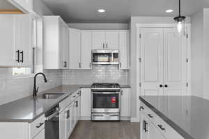 Kitchen with white cabinets, pendant lighting, stainless steel appliances, and sink