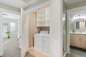 Washroom featuring light colored carpet, separate washer and dryer, and sink