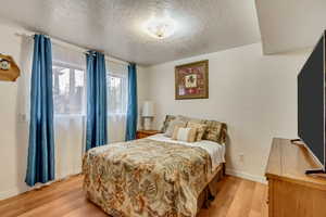 Bedroom featuring a textured ceiling and light hardwood / wood-style flooring