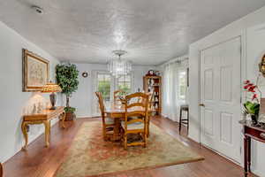 Dining area featuring hardwood / wood-style floors, a notable chandelier, and a textured ceiling