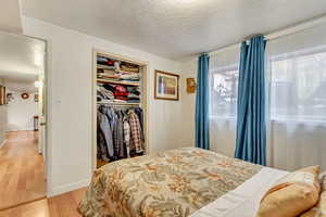 Bedroom with a closet, wood-type flooring, and a textured ceiling