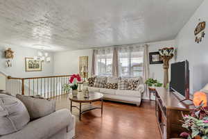 Living room with a textured ceiling, dark hardwood / wood-style flooring, and an inviting chandelier