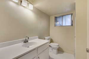 Bathroom featuring tile patterned flooring, vanity, a textured ceiling, and toilet