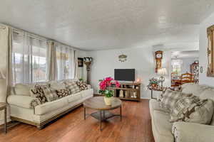 Living room featuring a textured ceiling, hardwood / wood-style flooring, and an inviting chandelier