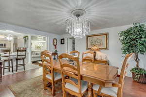 Dining room featuring hardwood / wood-style flooring, a notable chandelier, and a textured ceiling