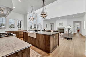 Kitchen featuring extractor fan, sink, a large island with sink, light hardwood / wood-style flooring, and a notable chandelier