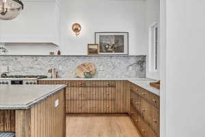 Kitchen featuring tasteful backsplash, stainless steel stove, and light hardwood / wood-style flooring