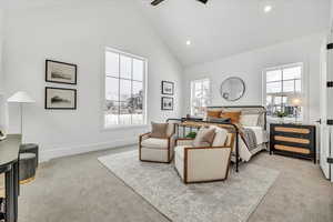 Carpeted bedroom featuring ceiling fan and high vaulted ceiling