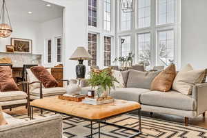 Living room with light hardwood / wood-style flooring, a towering ceiling, and an inviting chandelier