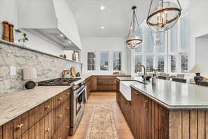 Kitchen featuring pendant lighting, sink, high end stainless steel range oven, light wood-type flooring, and a chandelier