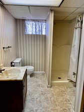 Bathroom with a shower with shower curtain, a drop ceiling, vanity, tile patterned flooring, and toilet